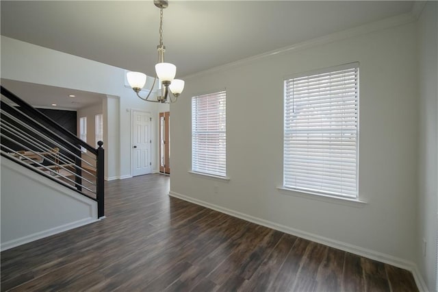 spare room featuring ornamental molding, dark hardwood / wood-style floors, and an inviting chandelier