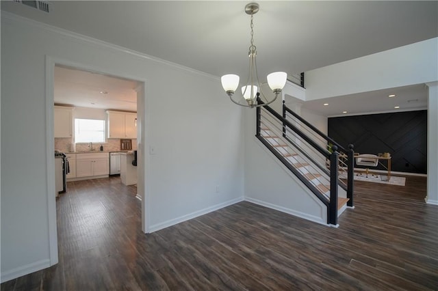 unfurnished dining area featuring dark hardwood / wood-style flooring, sink, crown molding, and a chandelier