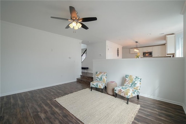 living area featuring crown molding, dark wood-type flooring, and ceiling fan