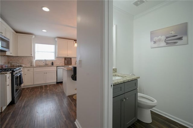 kitchen with backsplash, light stone countertops, white cabinets, and appliances with stainless steel finishes