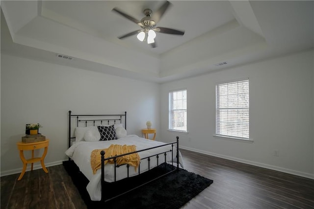 bedroom featuring dark wood-type flooring, ceiling fan, and a tray ceiling