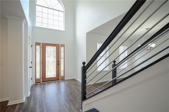 entrance foyer with an inviting chandelier, crown molding, dark wood-type flooring, and a high ceiling