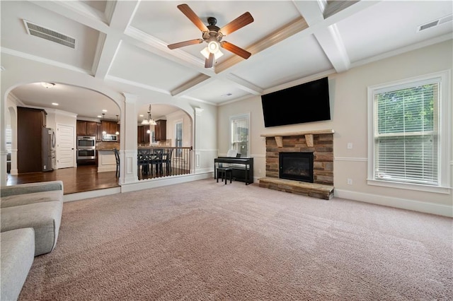 carpeted living room featuring a healthy amount of sunlight, visible vents, arched walkways, a fireplace, and coffered ceiling