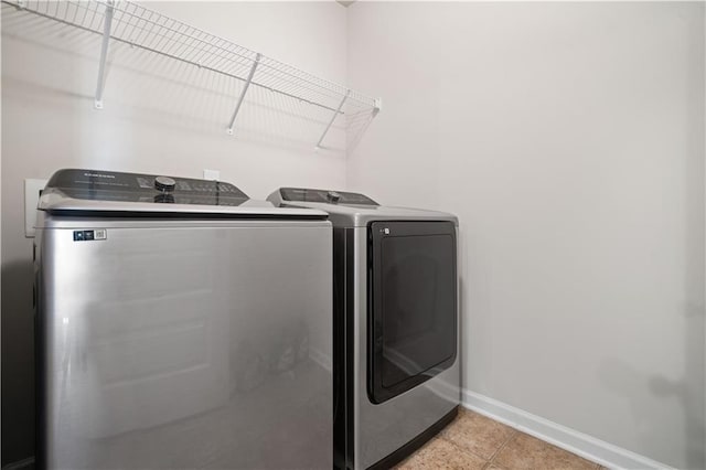 laundry room with washer and dryer, light tile patterned flooring, baseboards, and laundry area