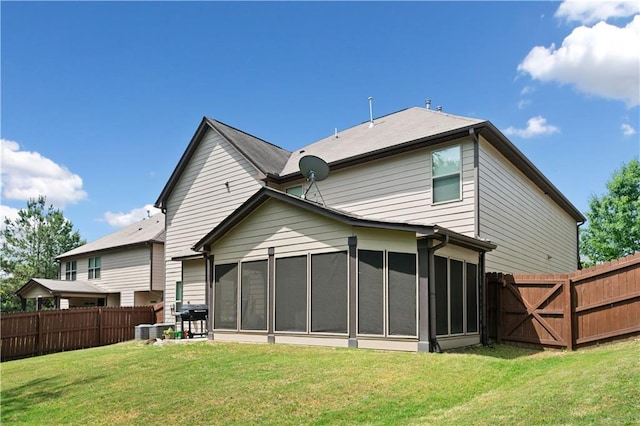 back of house featuring a sunroom, a fenced backyard, a lawn, and central AC