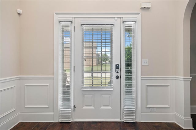 interior space featuring a healthy amount of sunlight, arched walkways, a wainscoted wall, and dark wood-style floors