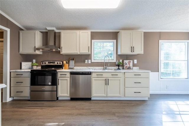 kitchen featuring hardwood / wood-style floors, appliances with stainless steel finishes, a textured ceiling, wall chimney exhaust hood, and sink