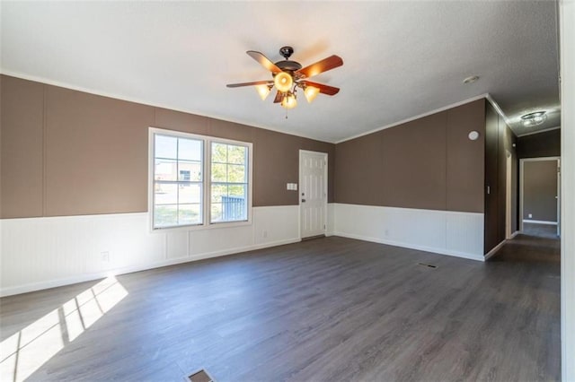 unfurnished room with crown molding, a textured ceiling, dark wood-type flooring, and ceiling fan