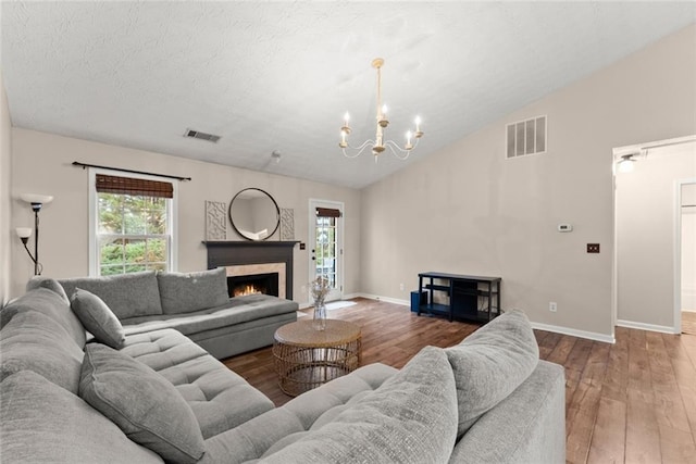 living room with lofted ceiling, a high end fireplace, visible vents, baseboards, and hardwood / wood-style floors