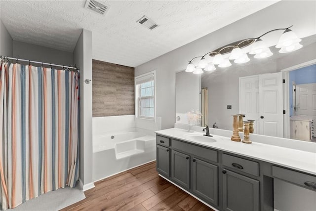 bathroom featuring a garden tub, visible vents, wood finished floors, and vanity