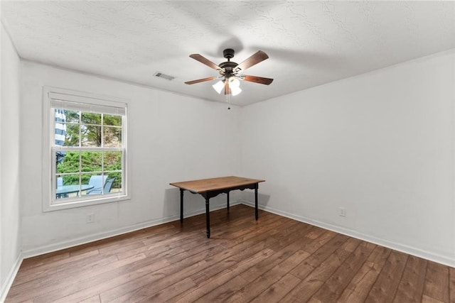 empty room with a ceiling fan, wood-type flooring, visible vents, and a textured ceiling