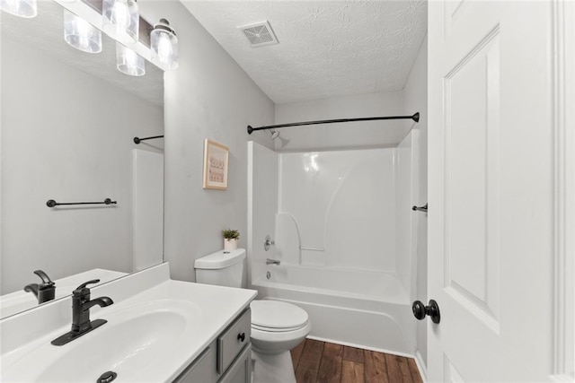 bathroom with visible vents, toilet, vanity, a textured ceiling, and wood finished floors