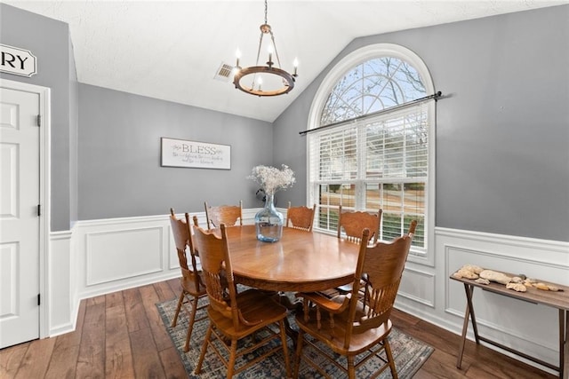 dining space featuring lofted ceiling, wood-type flooring, a wealth of natural light, and an inviting chandelier