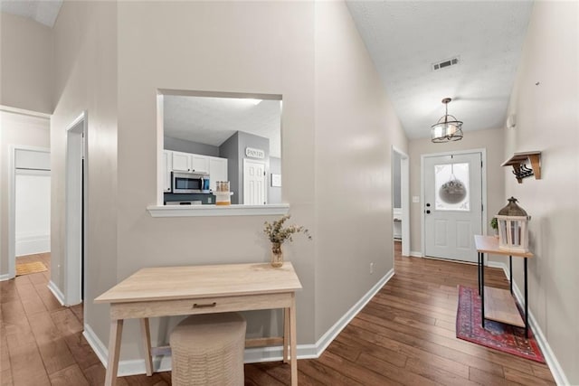 entrance foyer featuring visible vents, vaulted ceiling, baseboards, and hardwood / wood-style flooring