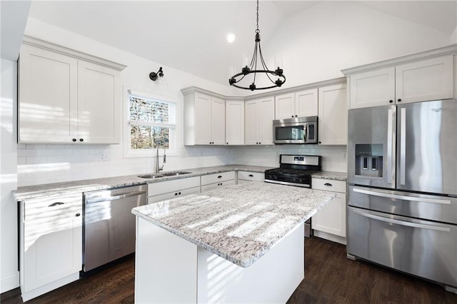 kitchen featuring vaulted ceiling, appliances with stainless steel finishes, a sink, and dark wood-style floors