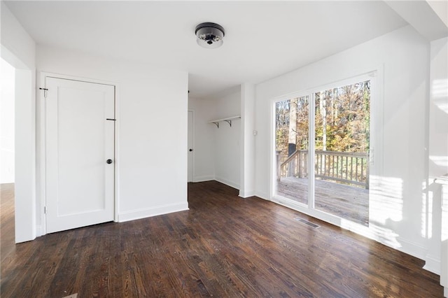 unfurnished bedroom featuring baseboards, wood finished floors, visible vents, and access to exterior