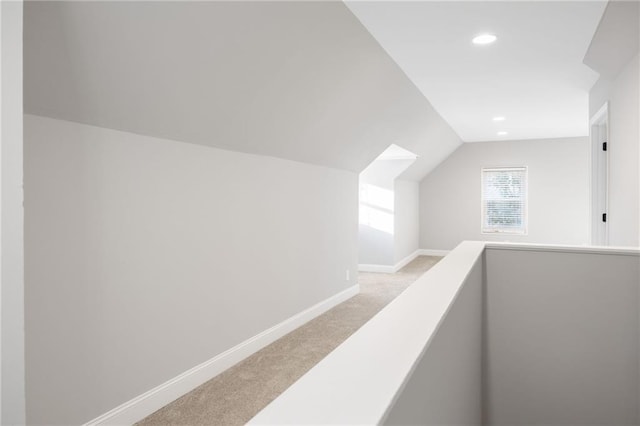 hallway with lofted ceiling, recessed lighting, light colored carpet, an upstairs landing, and baseboards