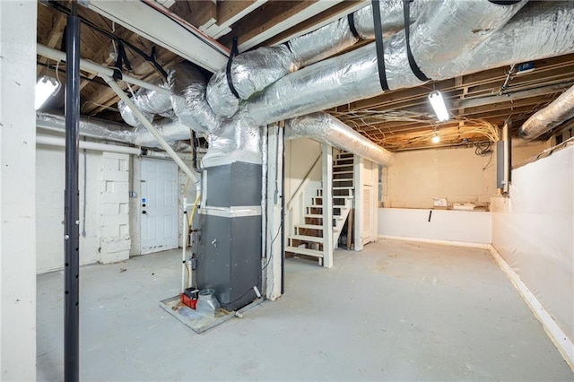 unfinished basement featuring heating unit, electric panel, and stairs