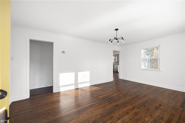 empty room with a chandelier, ornamental molding, dark wood finished floors, and baseboards