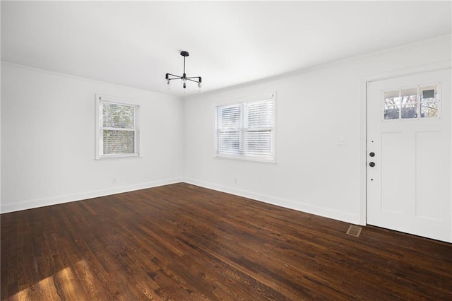 interior space featuring ornamental molding, dark wood-style flooring, an inviting chandelier, and baseboards