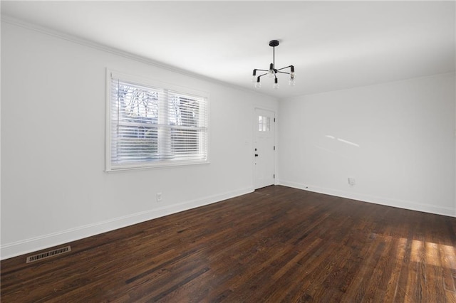 spare room featuring baseboards, visible vents, ornamental molding, dark wood-style flooring, and an inviting chandelier