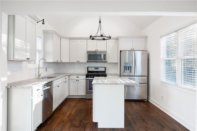 kitchen with light stone counters, a notable chandelier, stainless steel appliances, decorative backsplash, and a sink