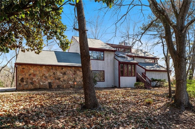 view of side of home with stone siding and a chimney