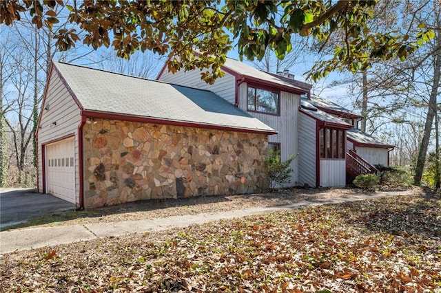 view of side of property featuring stone siding and driveway