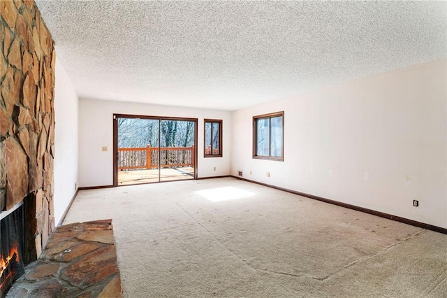 spare room featuring carpet, a fireplace, and baseboards