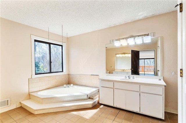 full bathroom with visible vents, a textured ceiling, vanity, a bath, and tile patterned floors