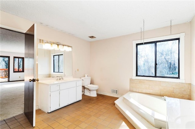 bathroom featuring visible vents, toilet, a textured ceiling, vanity, and a bath