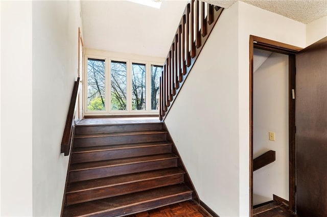 stairway with a textured ceiling and baseboards