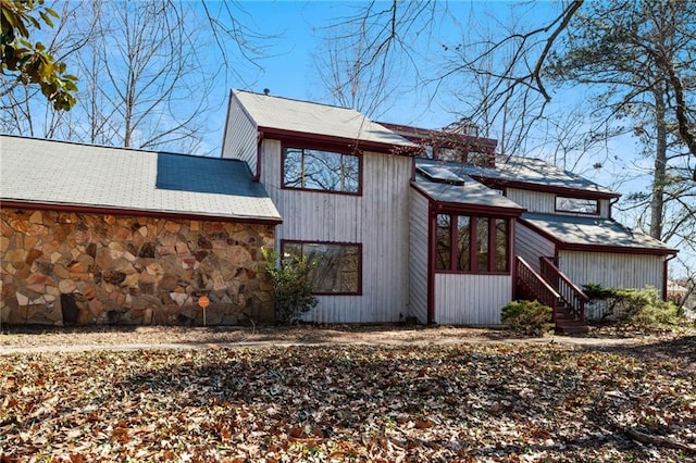 view of property exterior featuring stone siding and a chimney