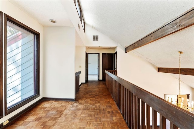 hall featuring baseboards, visible vents, vaulted ceiling with beams, an inviting chandelier, and a textured ceiling