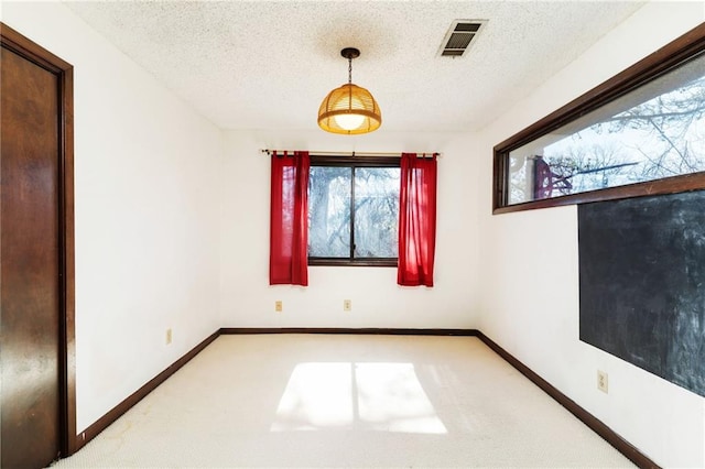 carpeted spare room featuring visible vents, a textured ceiling, and baseboards