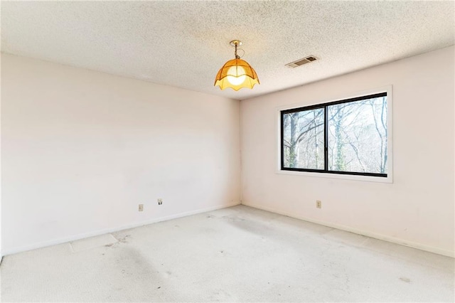 unfurnished room featuring baseboards, carpet, visible vents, and a textured ceiling