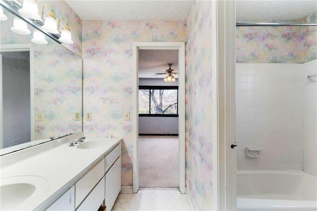 bathroom with a textured ceiling, a sink, double vanity, washtub / shower combination, and wallpapered walls