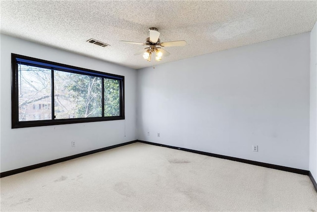 unfurnished room with a textured ceiling, carpet floors, a ceiling fan, visible vents, and baseboards