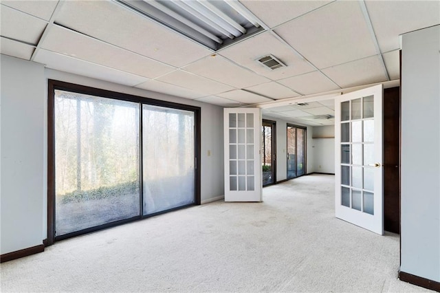 empty room featuring a drop ceiling, visible vents, baseboards, french doors, and carpet