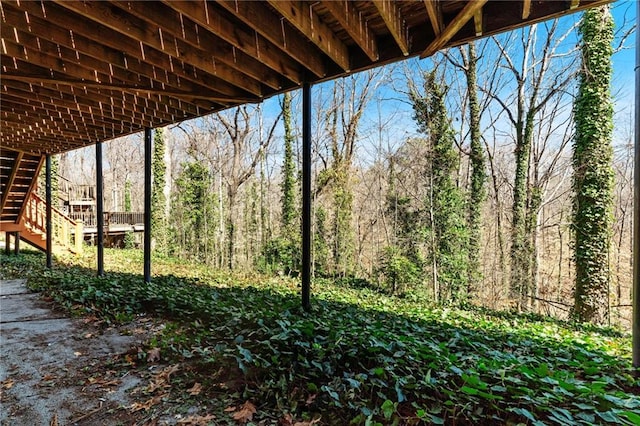 view of yard with stairs and a view of trees