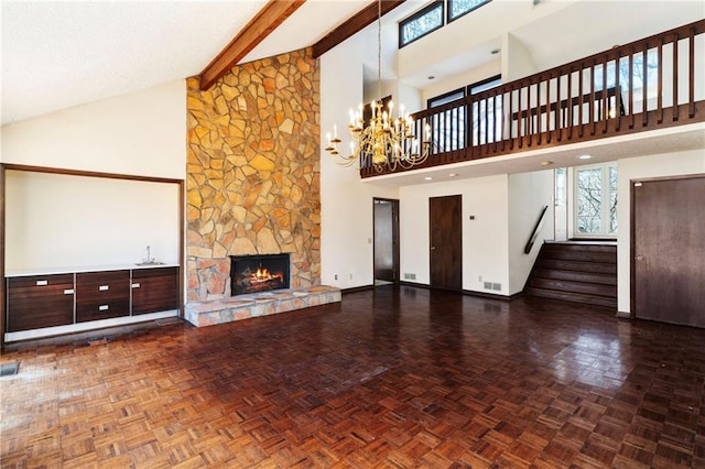 unfurnished living room with stairway, beamed ceiling, a wealth of natural light, and a stone fireplace