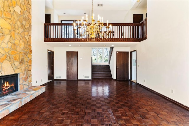 unfurnished living room featuring visible vents, an inviting chandelier, a stone fireplace, baseboards, and stairs