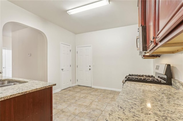 kitchen featuring stove, sink, and light stone countertops