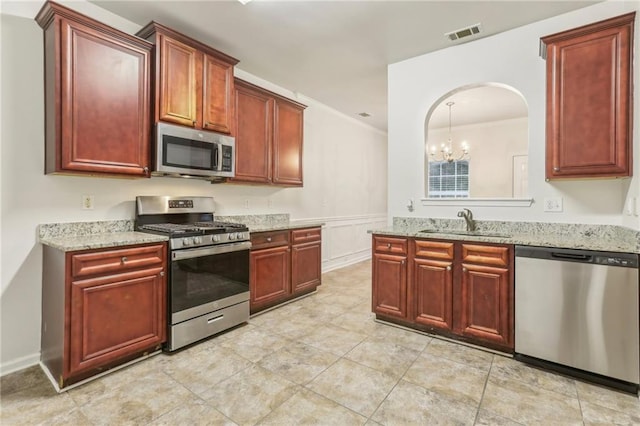 kitchen featuring sink, light stone countertops, an inviting chandelier, and appliances with stainless steel finishes