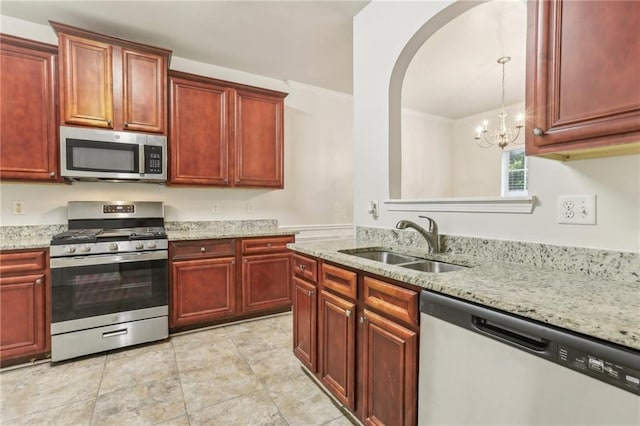 kitchen featuring hanging light fixtures, sink, ornamental molding, stainless steel appliances, and light stone counters