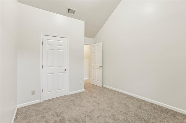 unfurnished bedroom with a closet, light carpet, and vaulted ceiling