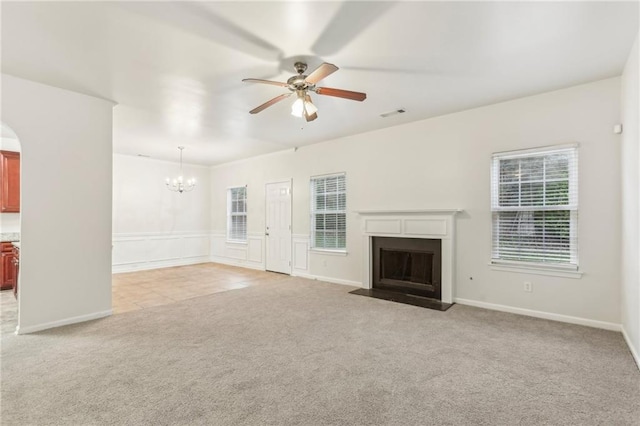 unfurnished living room featuring light carpet and ceiling fan with notable chandelier