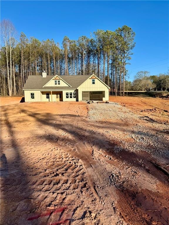 view of front of property with dirt driveway, board and batten siding, and a garage