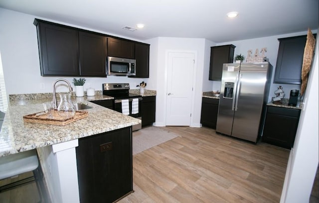 734 Great Oak Pl, Villa Rica, GA 30180 - kitchen featuring light wood-style flooring, a peninsula, visible vents, appliances with stainless steel finishes, and light stone counters