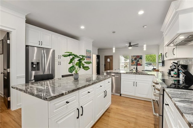 kitchen featuring a center island, white cabinetry, sink, pendant lighting, and stainless steel appliances